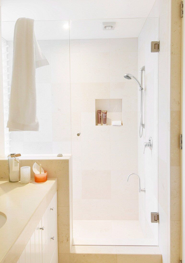 Modernes Bad, abgetrennter Duschbereich mit Glastür, sandfarbene Fliesen an Wand