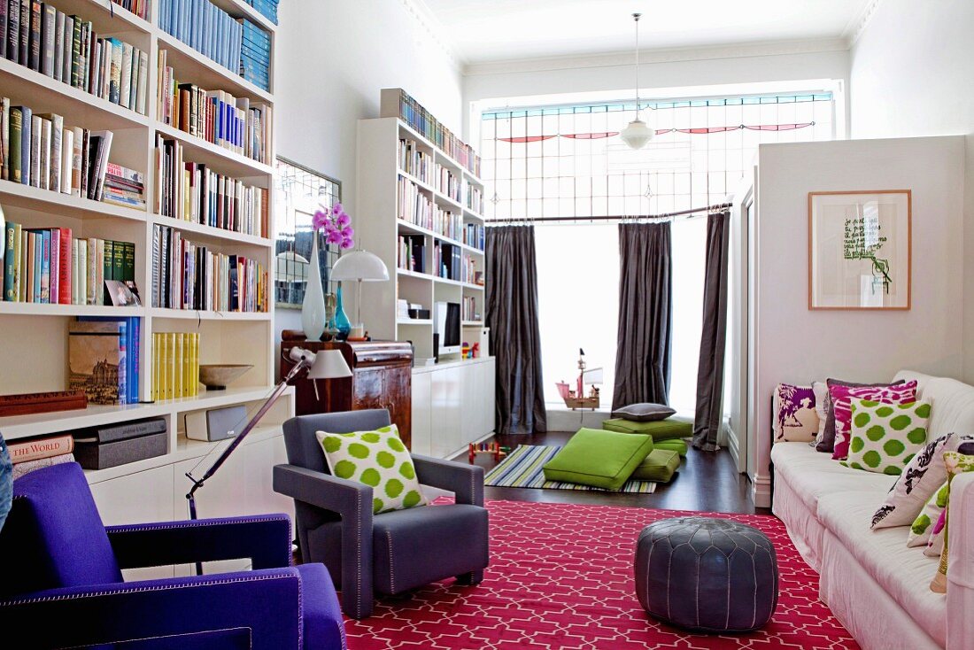 Former salesroom converted into spacious living room with colourful accessories and tall bookcases against wall