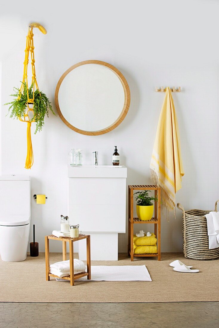 Round mirror above washstand, small wooden stool and yellow accessories