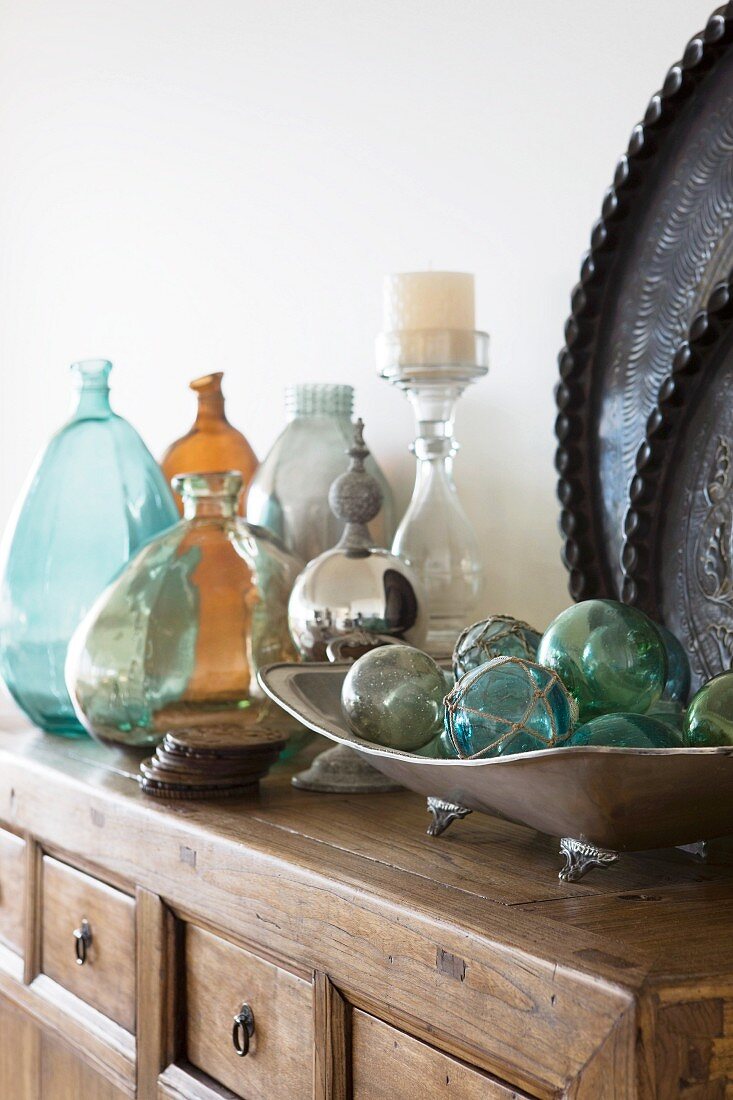 Schale mit Glaskugeln und Sammlung von Glasvasen auf Kommode aus Massivholz