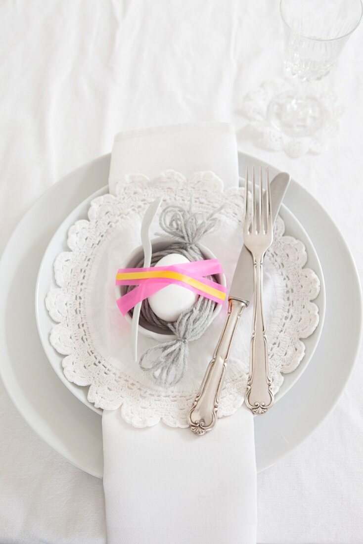 Egg in nest of woollen yarn on Easter place setting