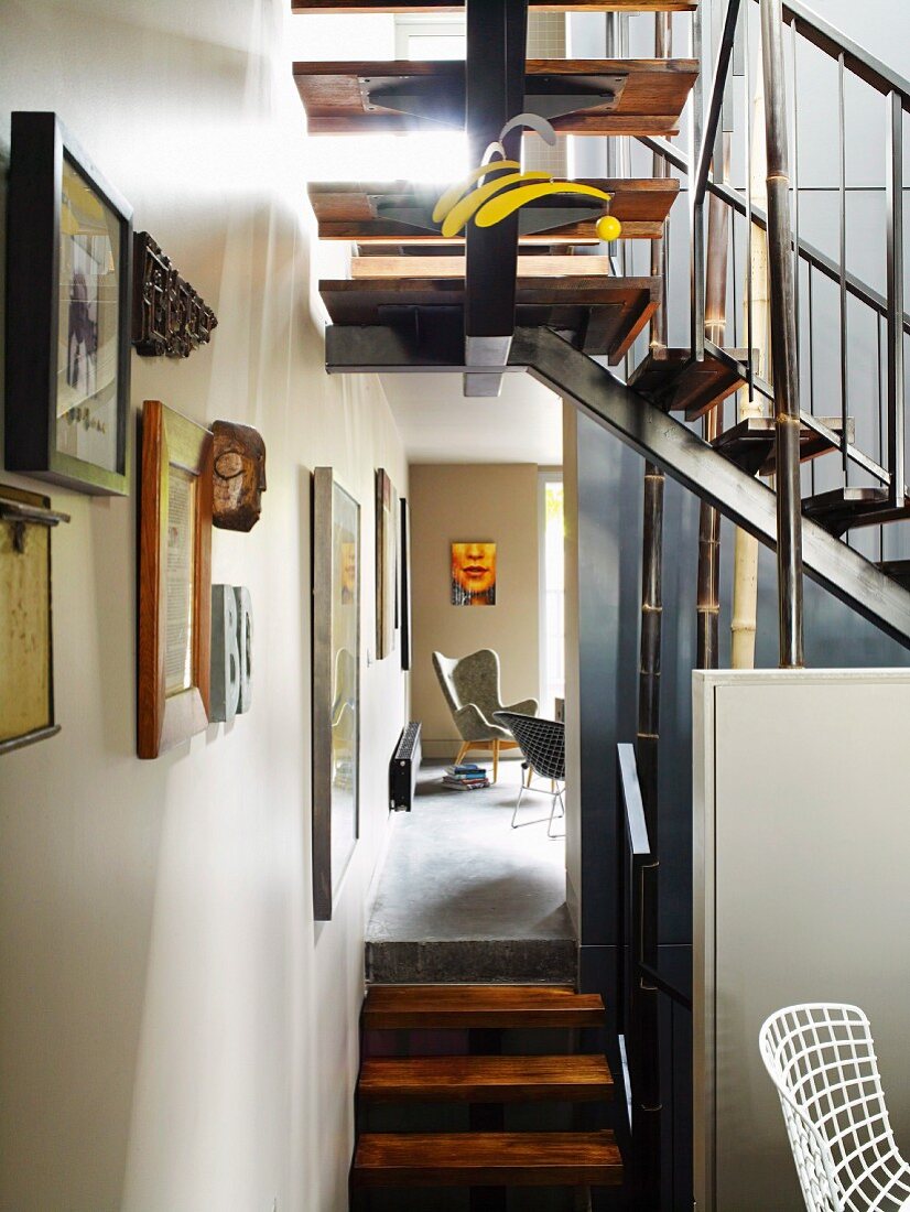 Offenes Treppenhaus mit mehrläufiger Treppe & Bambusstangen; dazwischen raumhoher Durchgang mit Blick auf Sitzecke