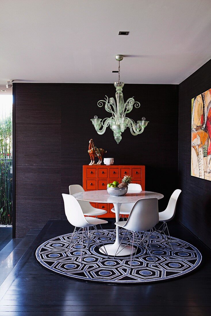 Runder Esstisch mit Schalenstühlen, Teppich & postmoderner Deckenleuchte auf Podest in Zimmerecke mit dunkler Holzverkleidung