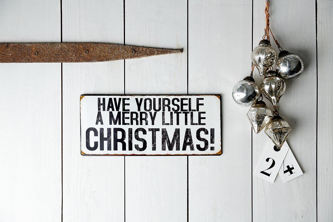 Sign (Have yourself a merry little Christmas) on wooden door next to baubles and tags