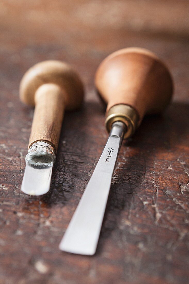 Two woodworking tools with wooden handles on rustic wooden surface