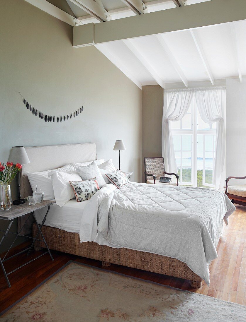 Doppelbett mit Komforthöhe und gepolstertem Kopfteil an schlammgrau getönter Wand in elegantem Schlafzimmer mit ländlichem Charme