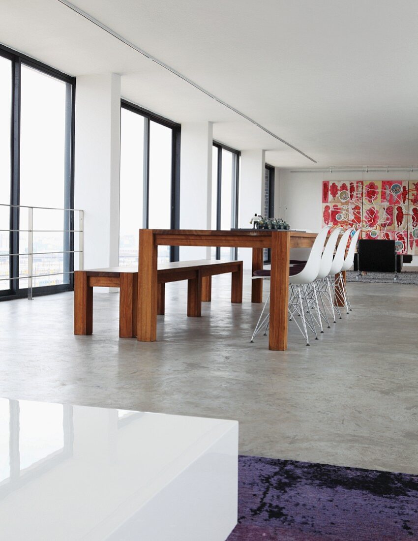 Modern dining area with bench and Eames shell chairs on polished concrete floor in Johannesburg art collector's loft apartment
