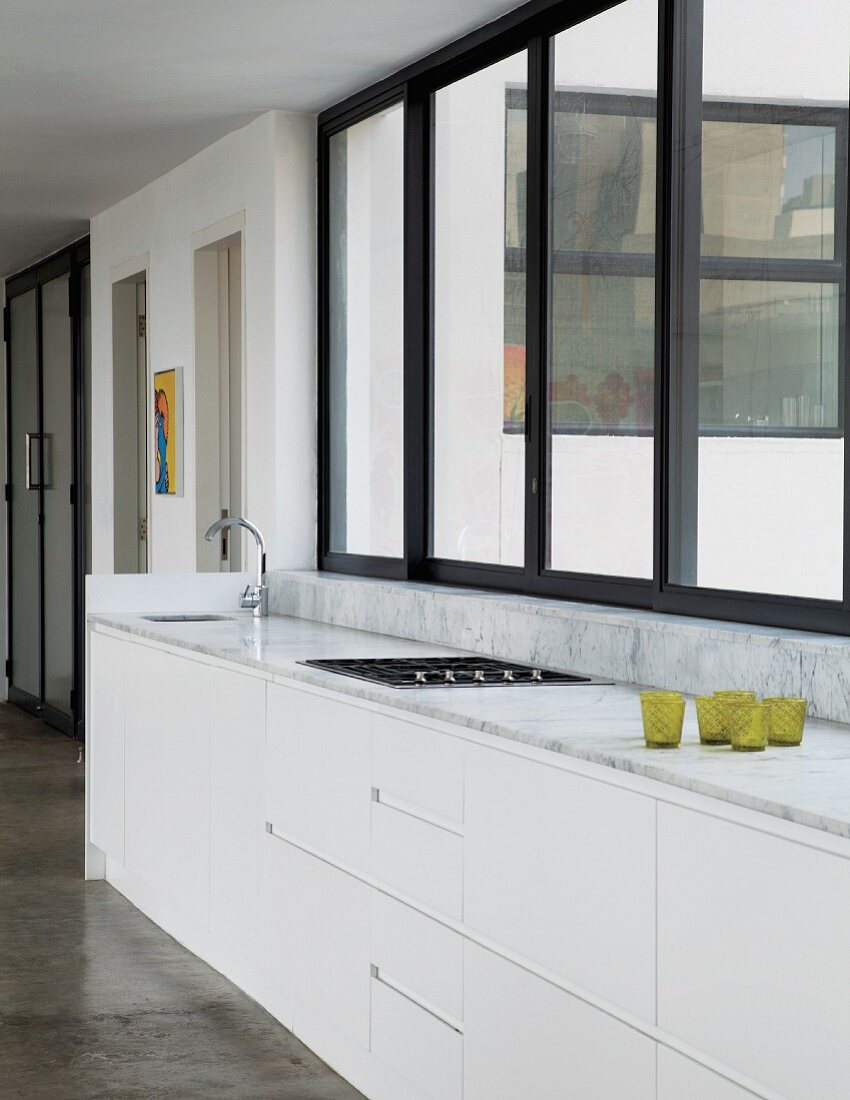 Puristische Küchenzeile mit Marmorplatte vor durchgehender Fensterfront