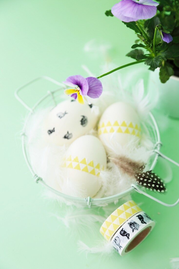 Easter arrangement; eggs decorated with washi tape and feathers in basket