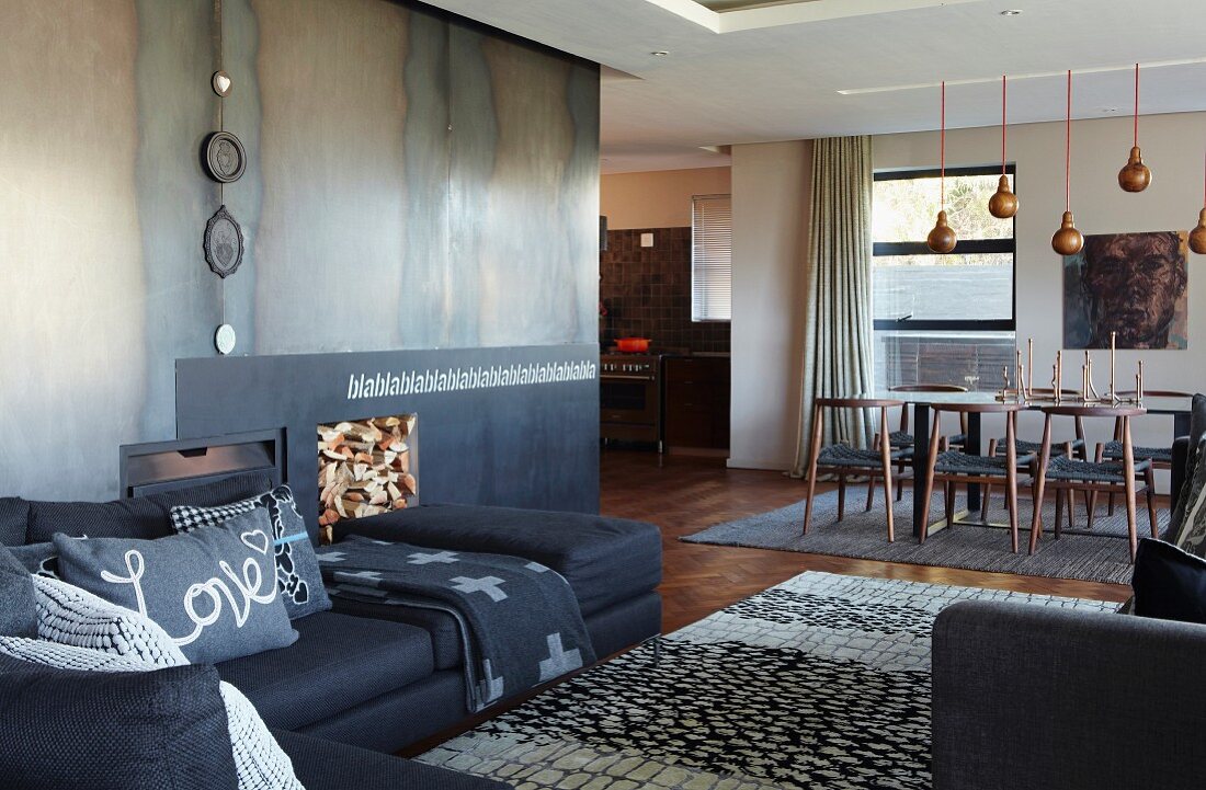 Open-plan, designer interior - sofa combination, rug, modern open fireplace with metal surround and dining area
