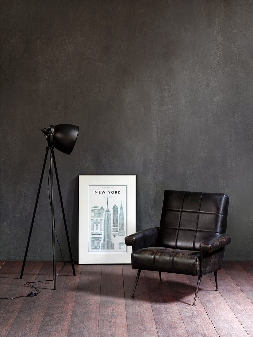 Retro leather armchair, black studio lamp and picture leaning against wall