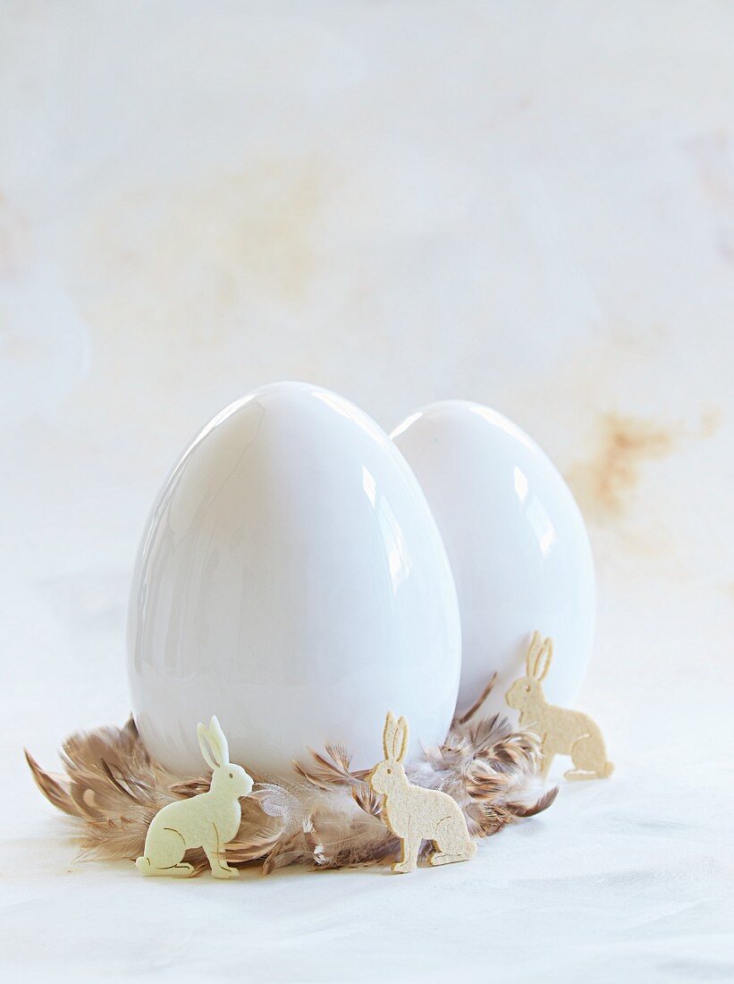 White eggs in nests of feathers with Easter bunnies