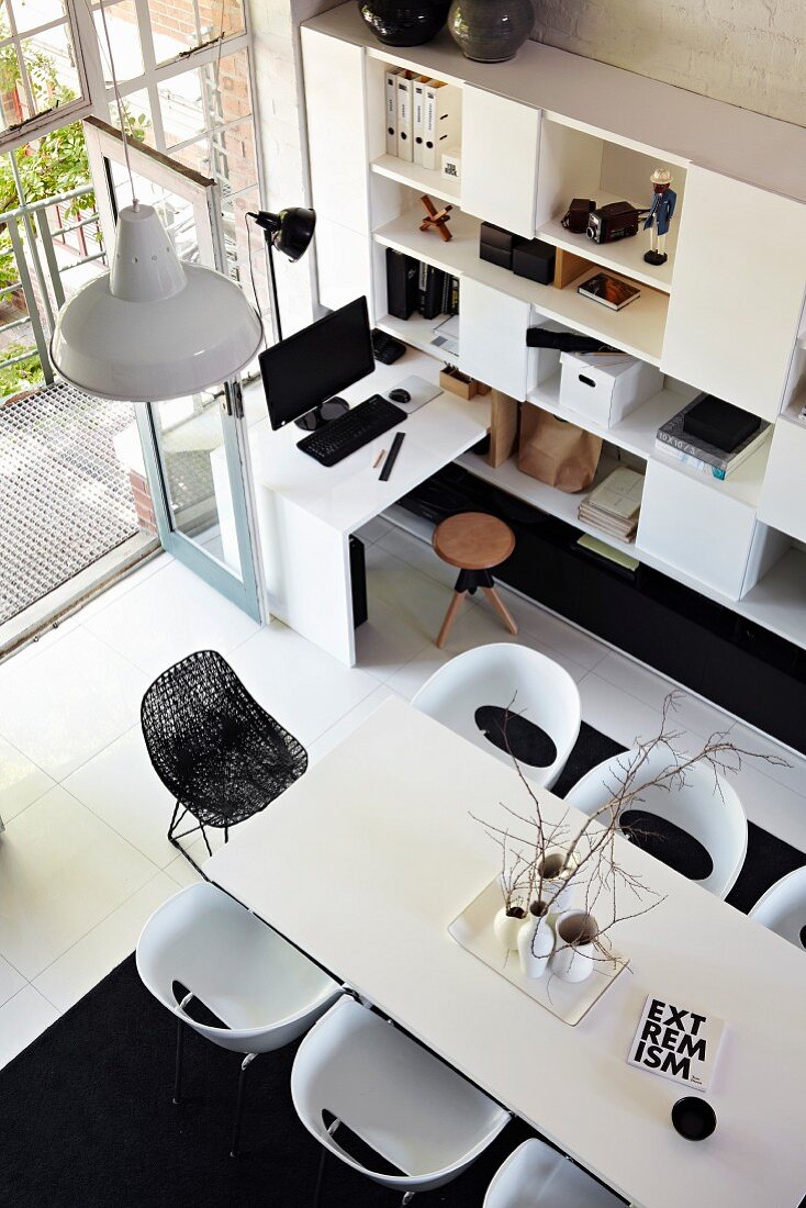 Blick von oben auf weissen Esstisch und moderne Stühle, gegenüber Regalschrank und integriertem Schreibplatz