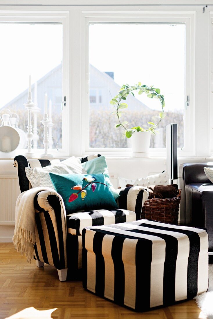 Sessel mit schwarz-weissen Blockstreifen und Fusshocker vor dem Wohnzimmerfenster