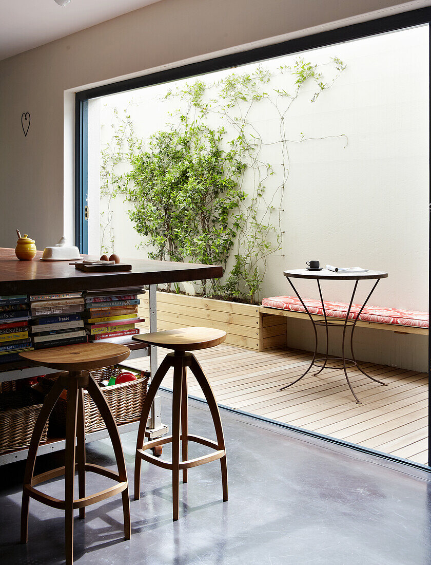 Kitchen island with storage space for books and vintage bar stool in front of patio door