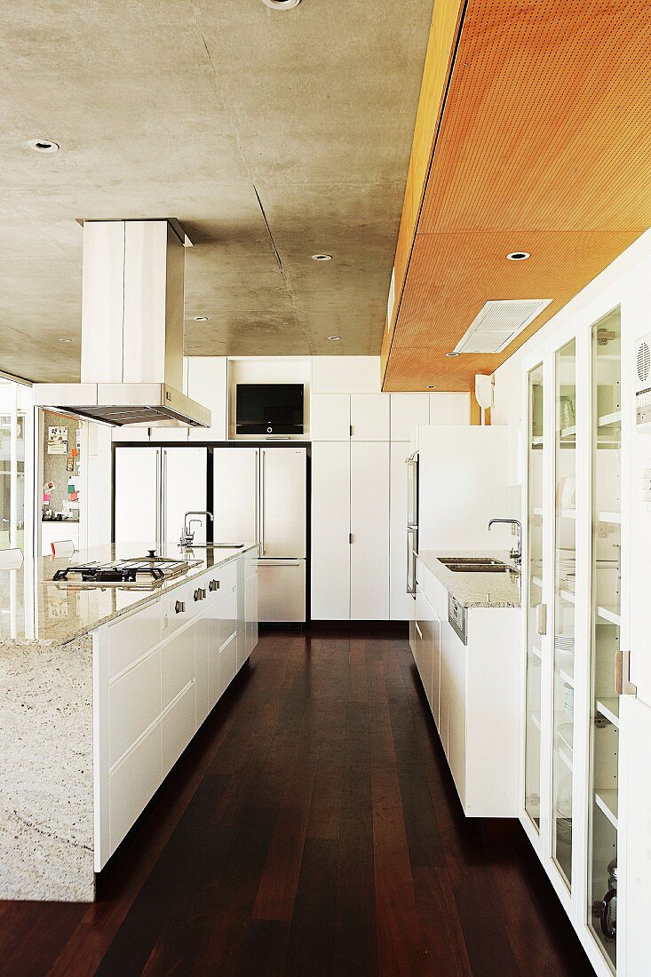 Moderne, weiße Küche mit freistehendem Mittelblock auf dunklem Dielenboden