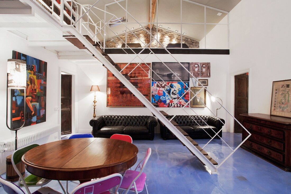 Filigrane Galerie Stahltreppe auf hellblauem Kunstharzboden in luftigem Wohnraum vor künstlerischer Bildergalerie