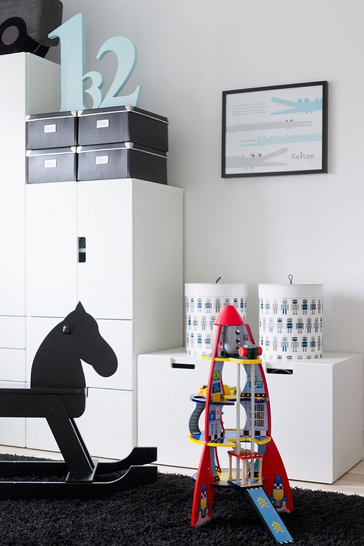 Modern, child's bedroom with robot and rocking horse in front of white, modern cupboard modules
