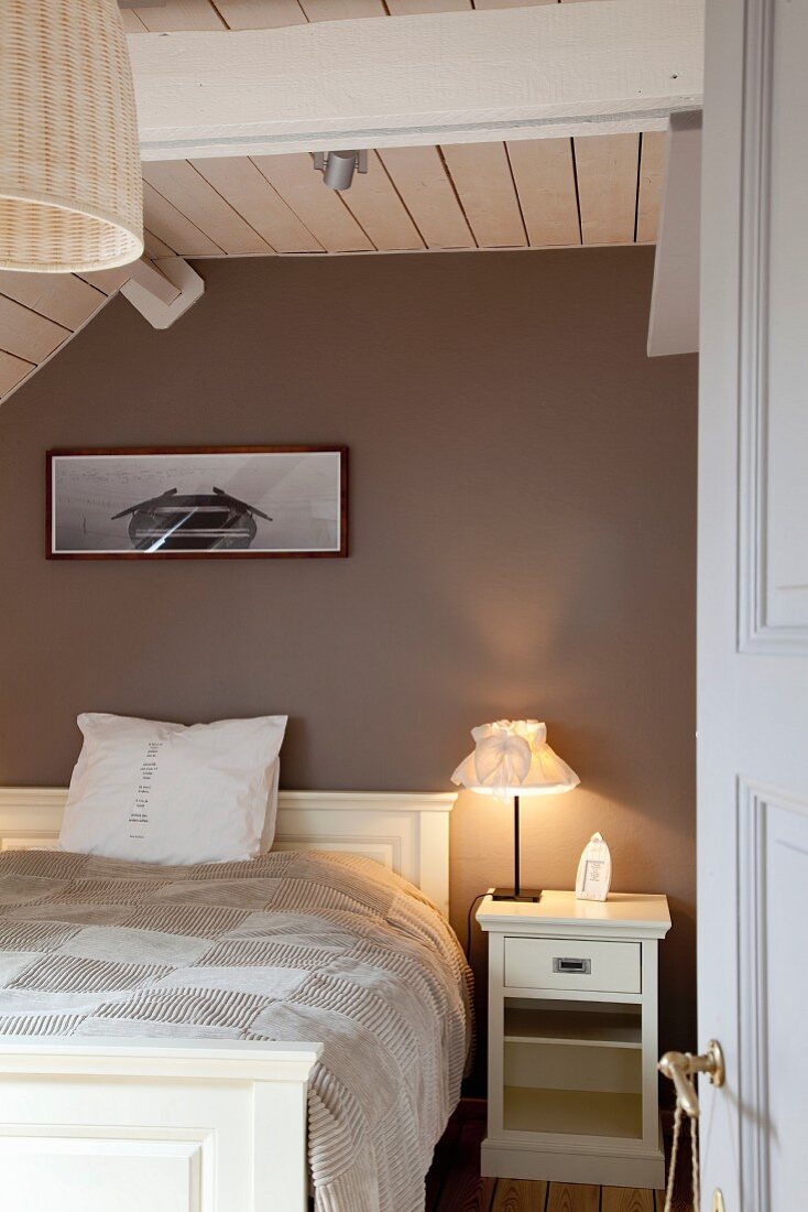 Holzverkleidetes Schlafzimmer mit weißem Doppelbett unter dem Dach