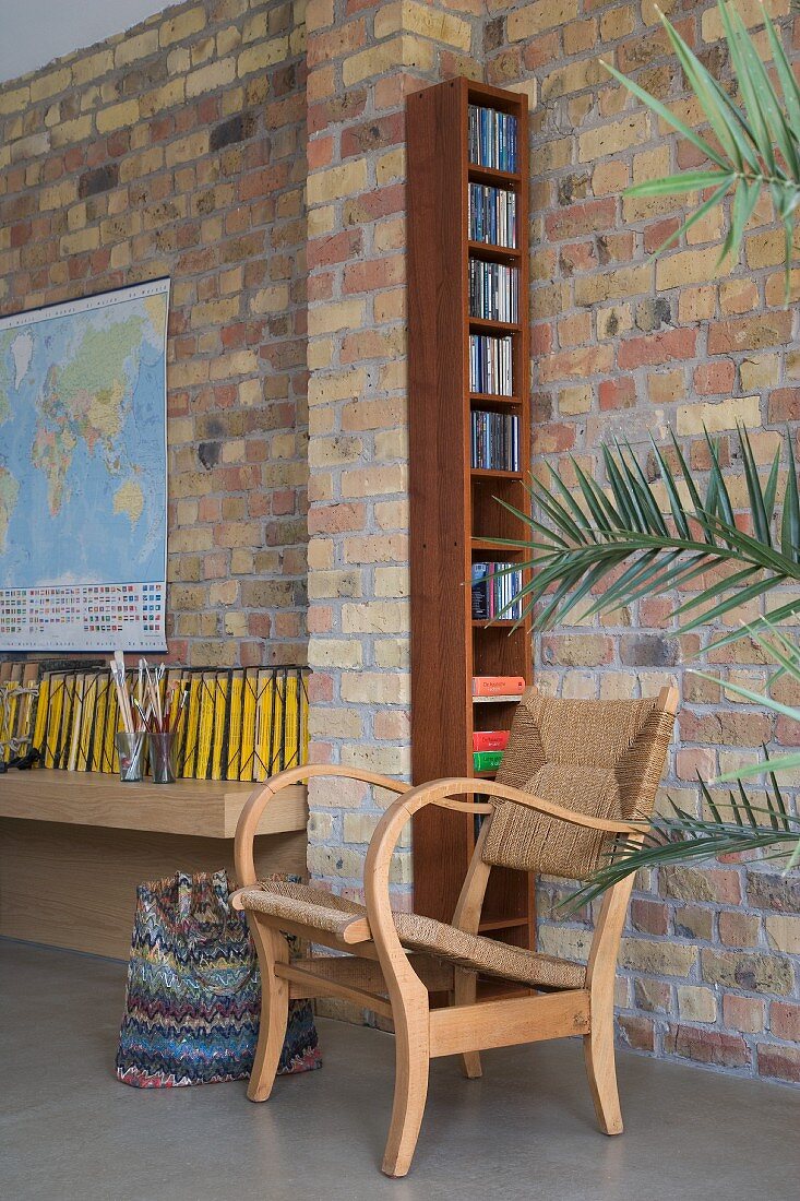 Rustic armchair against brick wall and narrow shelf unit against column
