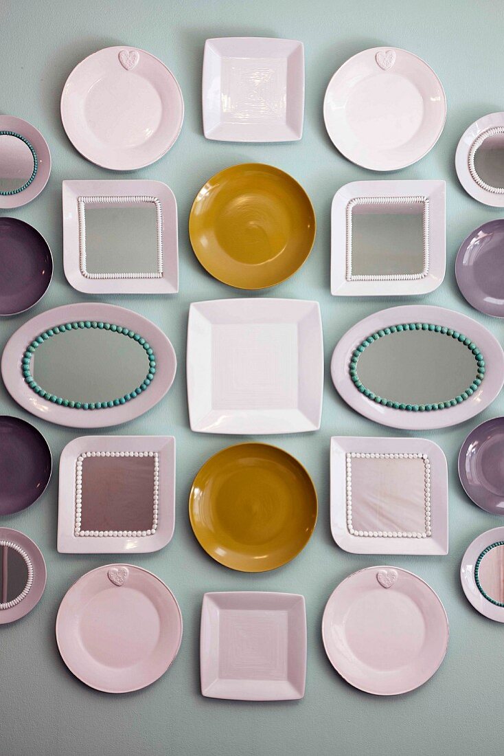 Collection of plates of various shapes hung on pale grey wall