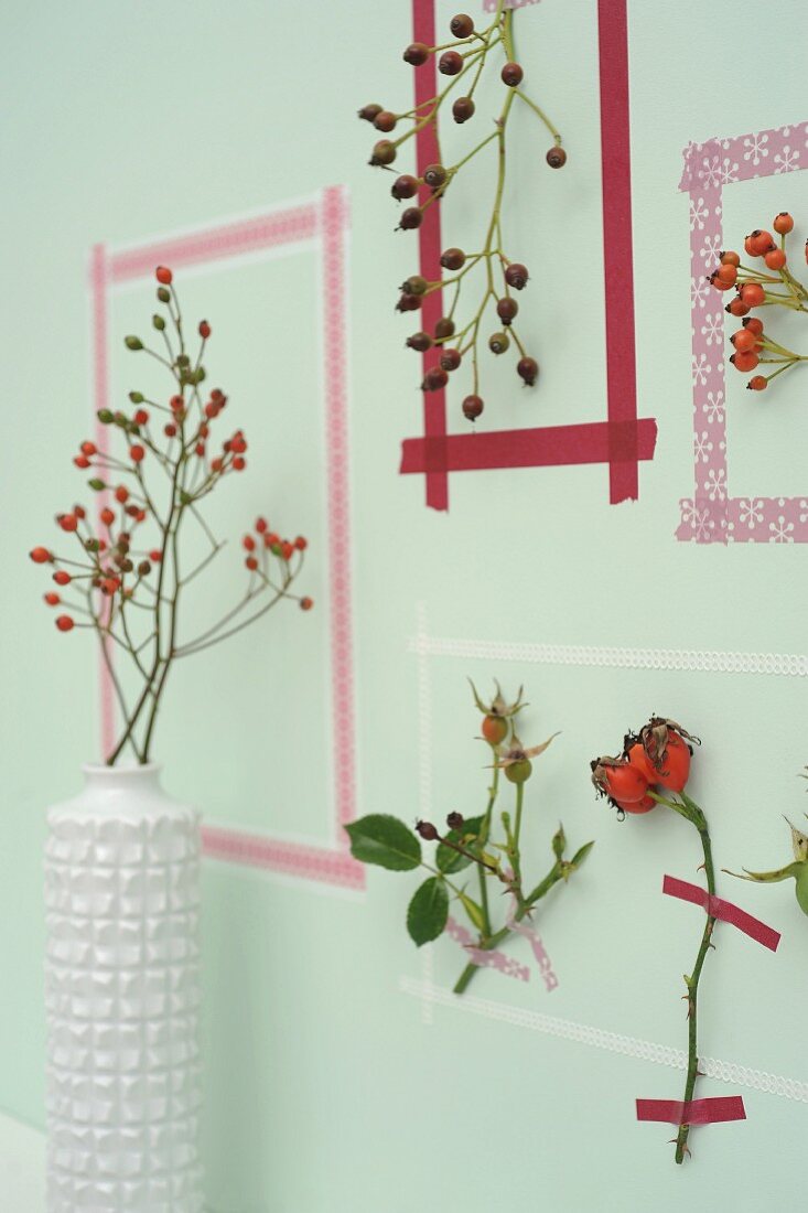 Picture frames made from washi tape around sprigs of rose hips on wall
