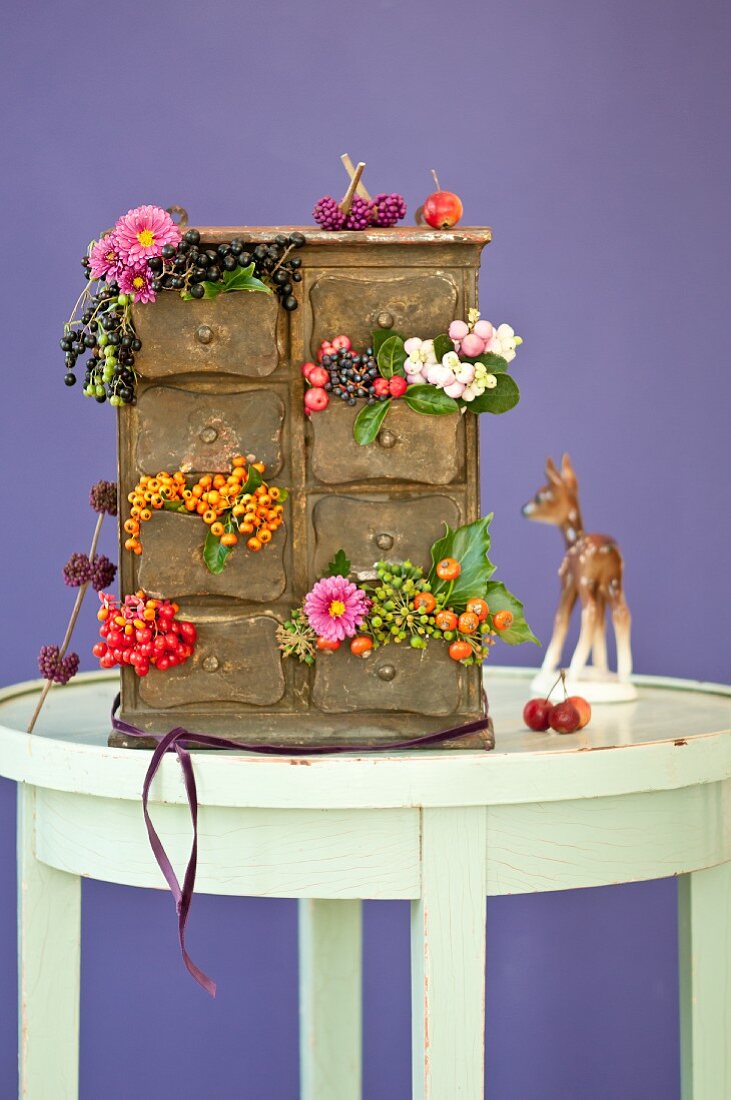 Kleines Schubladenschränkchen dekoriert mit herbstlichen Beeren & Blüten