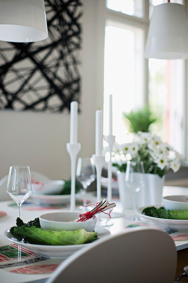 Gedecke mit weissen Schalen auf Gemüse- Deko und weiße Kerzenständer auf Tisch