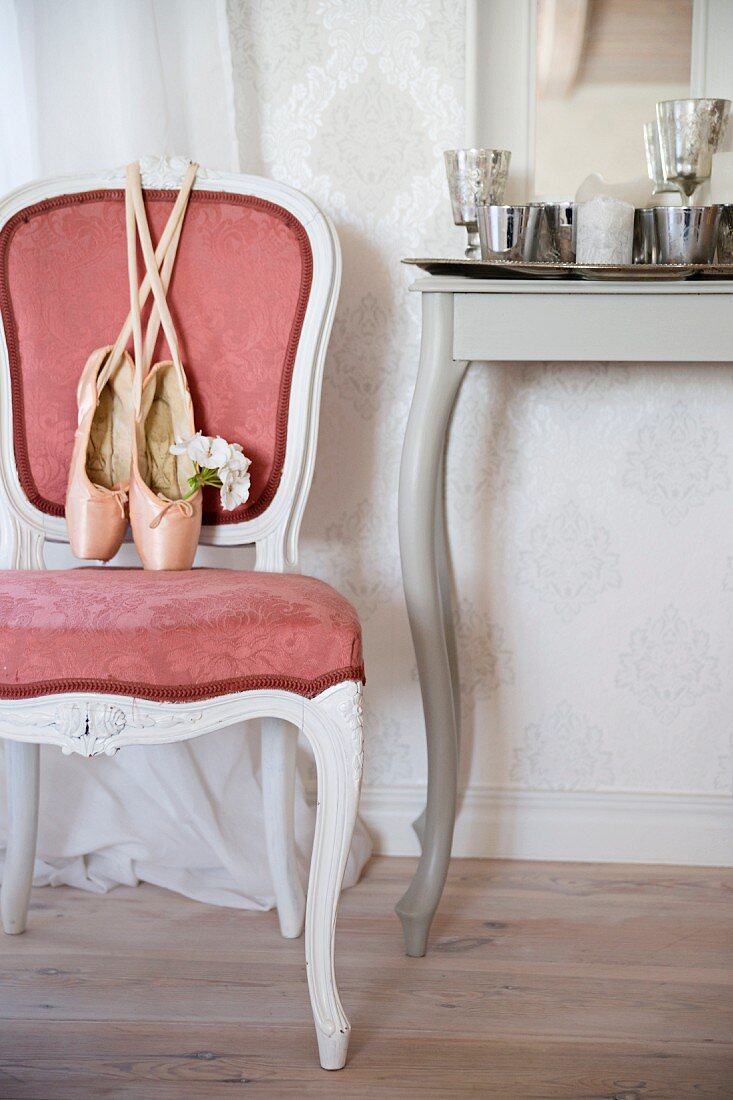Ballettschuhe auf Stuhl im Rokokostil mit rosa Samtbezug, neben Konsolentisch mit geschwungenen Beinen