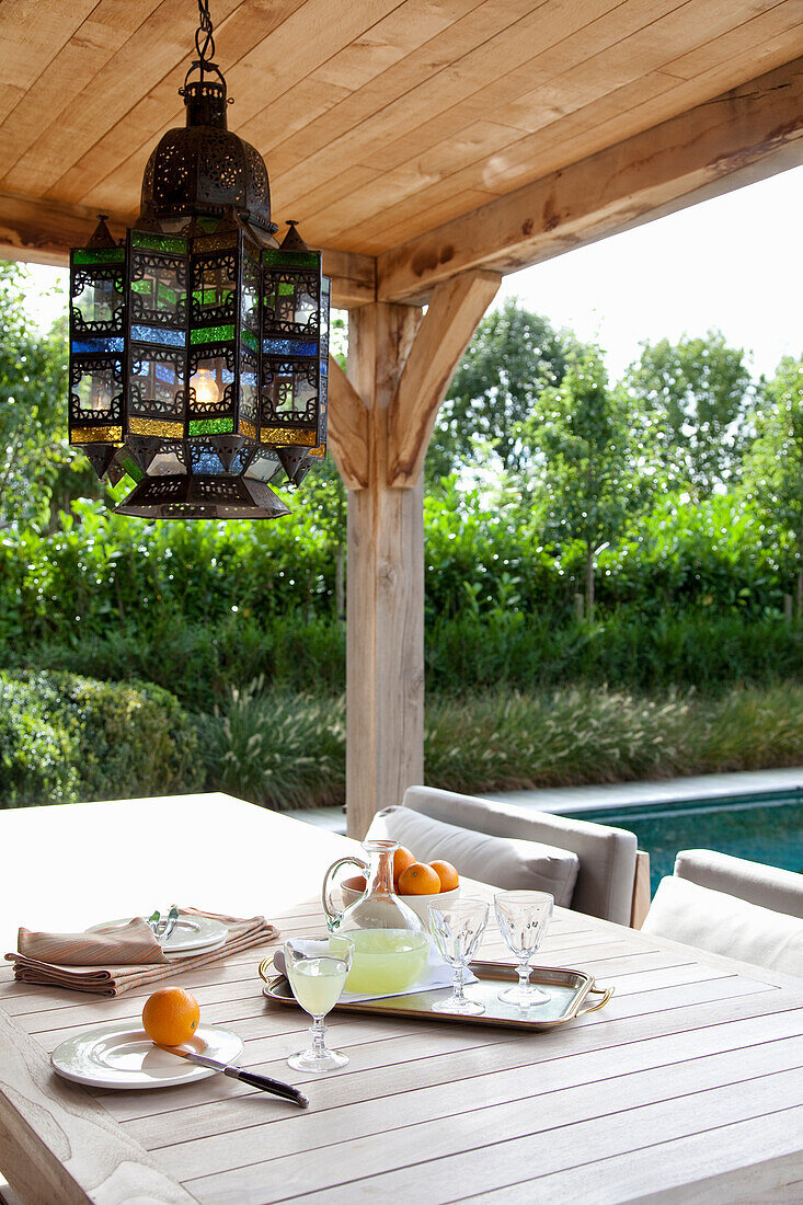 Set outdoor table under a pergola with oriental hanging lamp by the pool