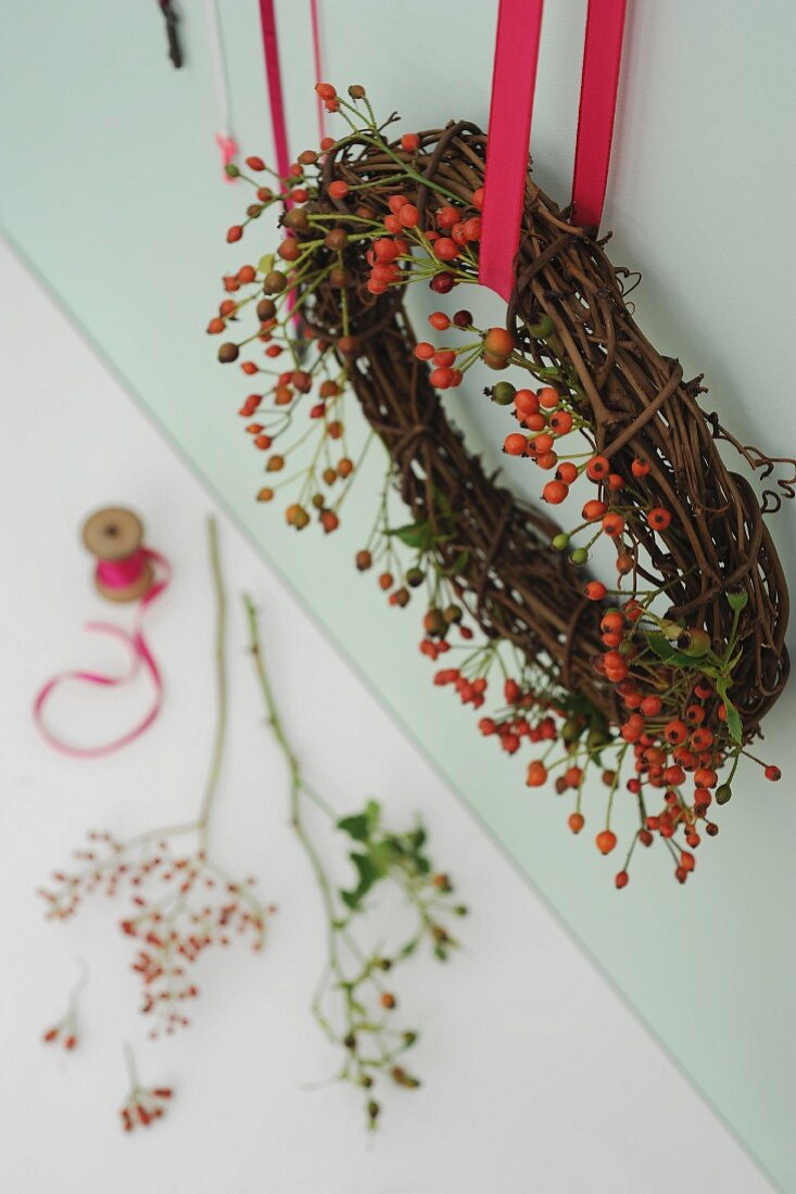 Willow and rose hip wreath hanging from red ribbon