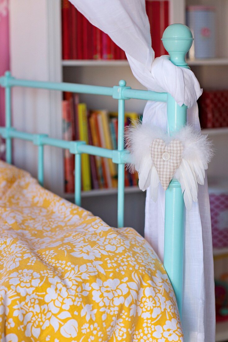 Detail of turquoise, lattice metal bed with white and yellow patterned bed linen