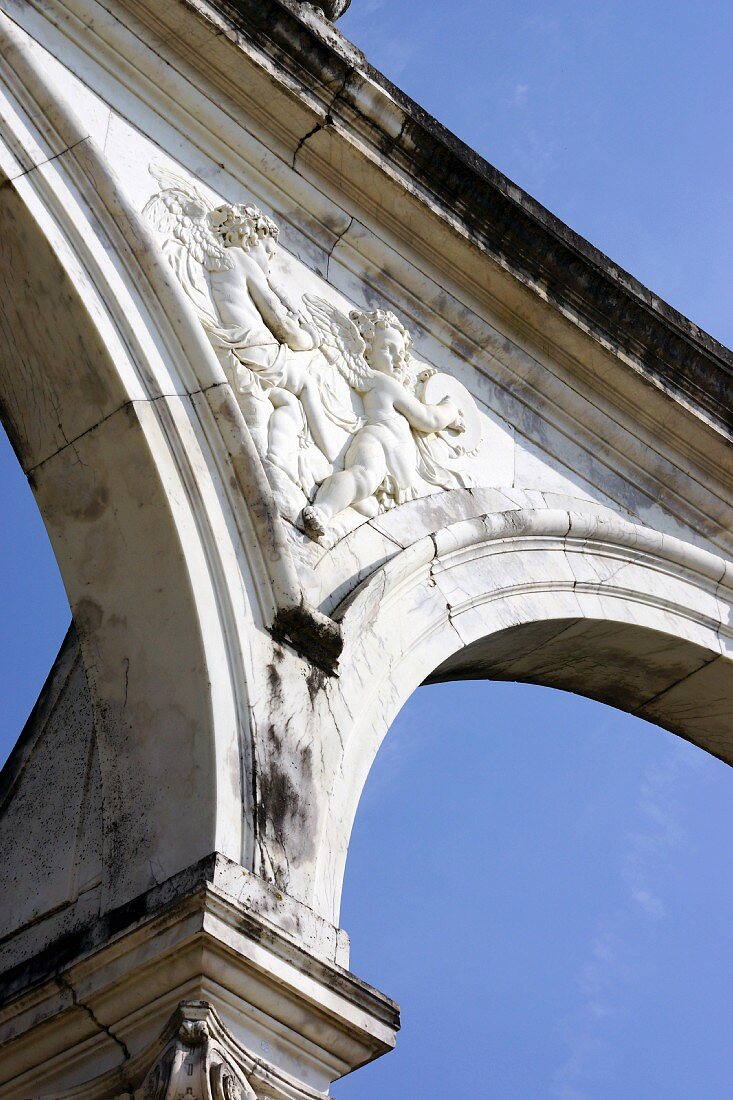 A view from underneath a round Baroque arch decorated with stone figures