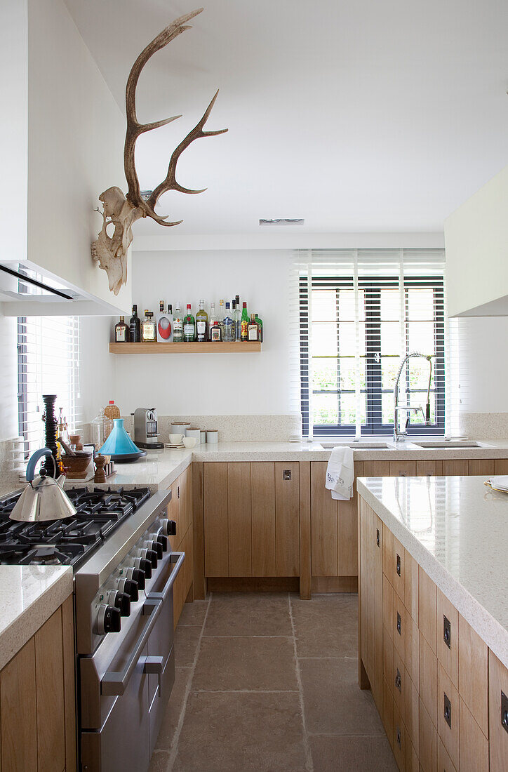 Country-style kitchen with deer antler decor and light-colored wooden cupboards