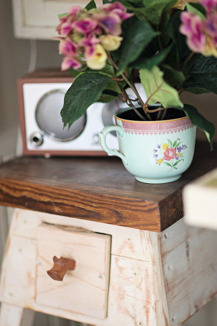Hortensie in Vintage Tasse gepflanzt auf rustikalem Blumenständer aus Holz