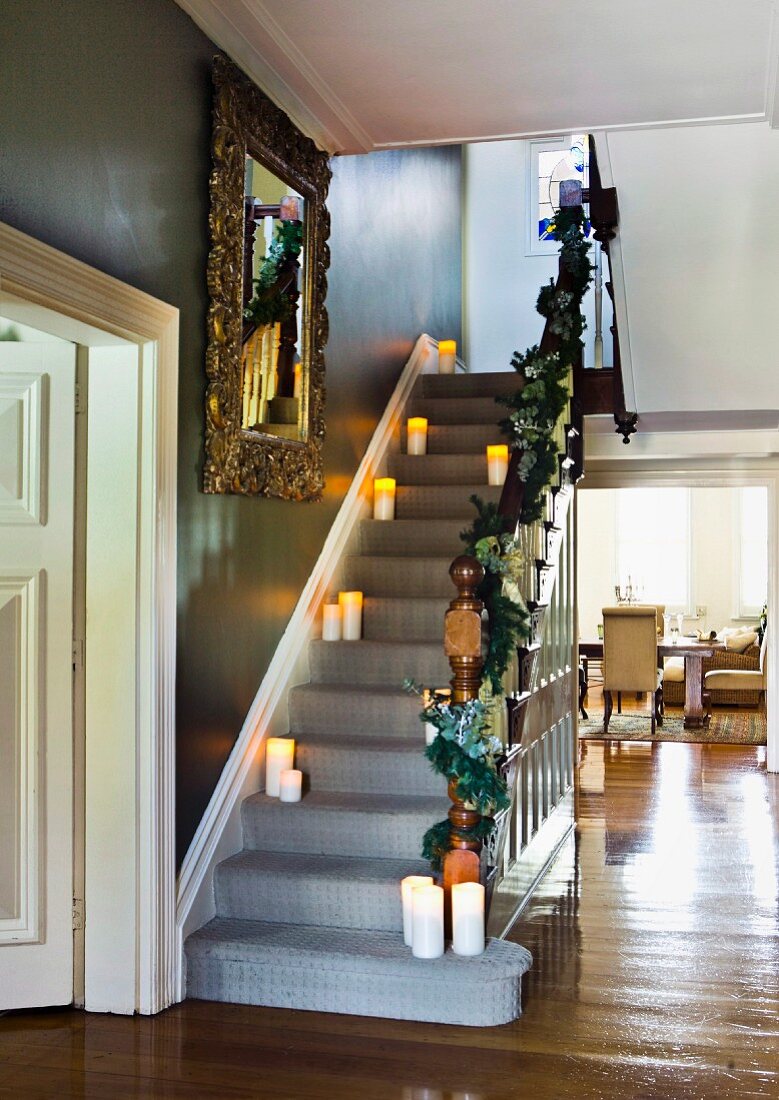 Lit candles on stair treads in hallway of traditional, elegant villa with view into living room through floor-to-ceiling open doorway