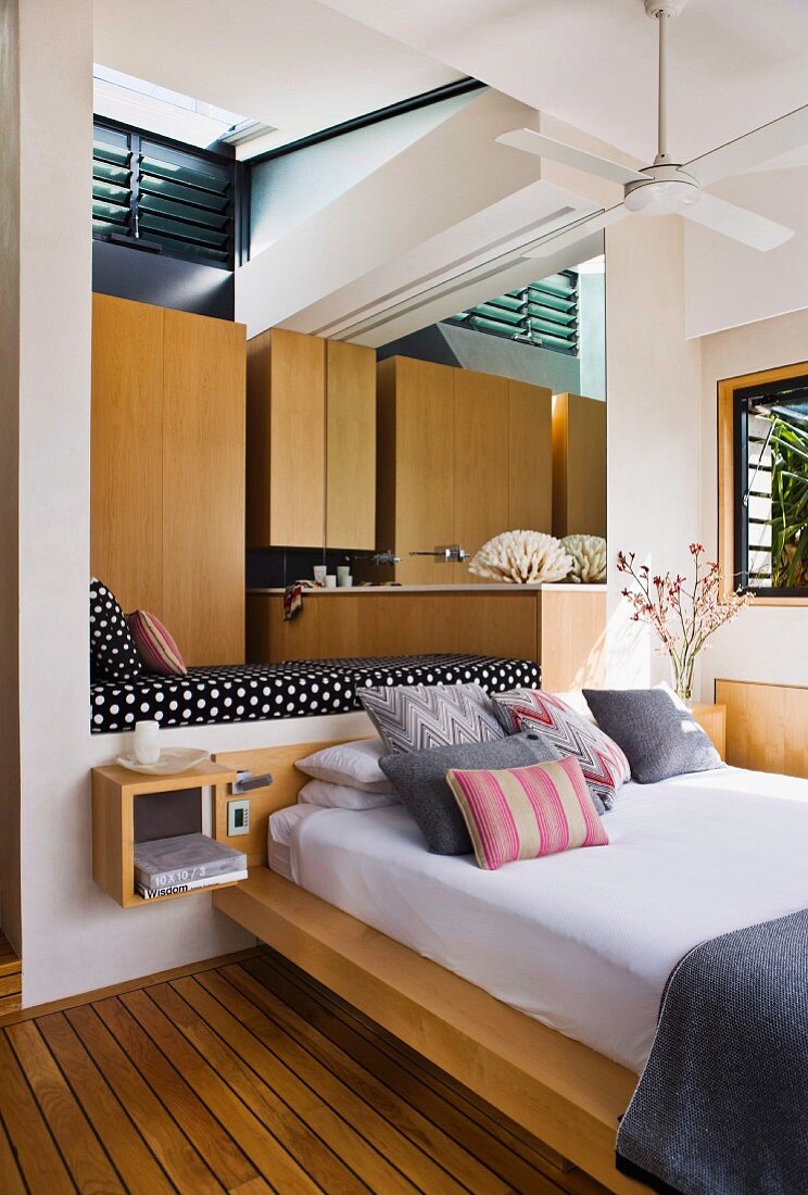 Stacked pillows on modern bed below daybed in niche in contemporary house