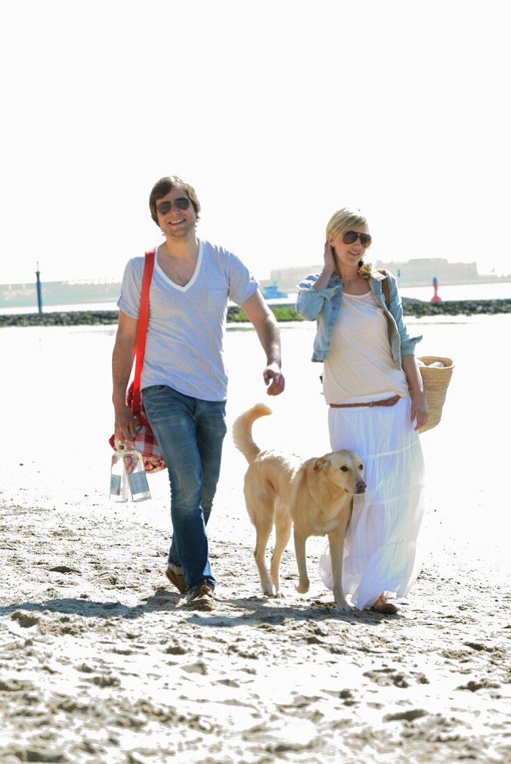 Couple and dog on their way to beach picnic