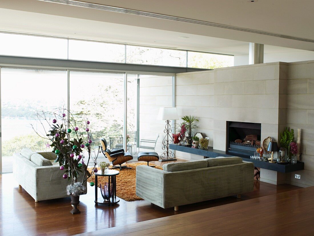 Modern lounge area with sofa set in contemporary house with glass wall