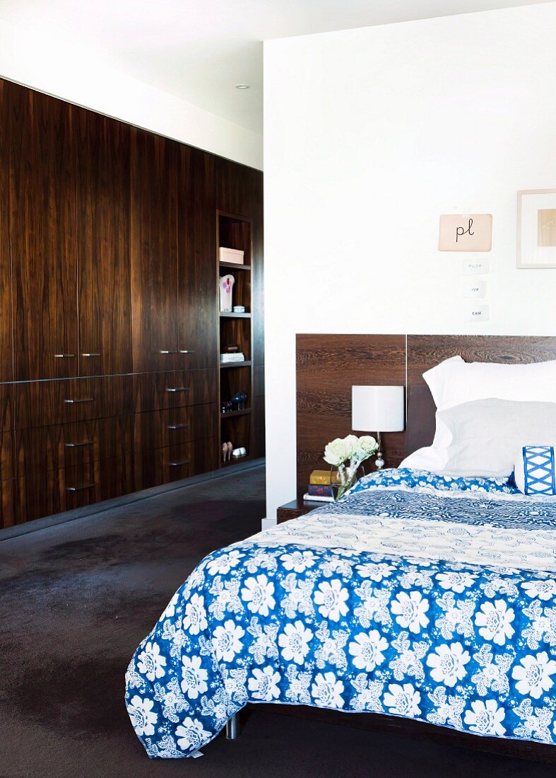 Schlafzimmer mit blauweiss bezogenem Doppelbett; seitlicher Gang mit Einbauschrank aus dunklem Holz