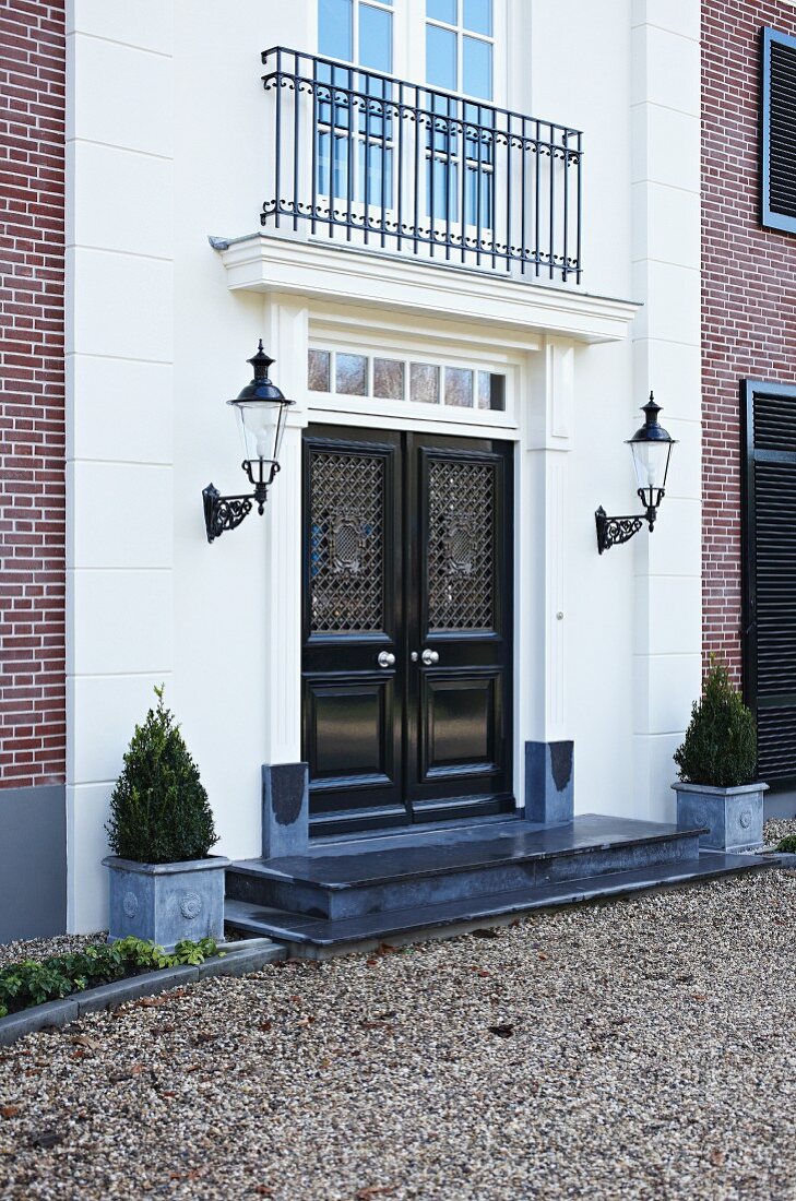 Entrance of prestigious villa with double doors flanked by sconce lanterns