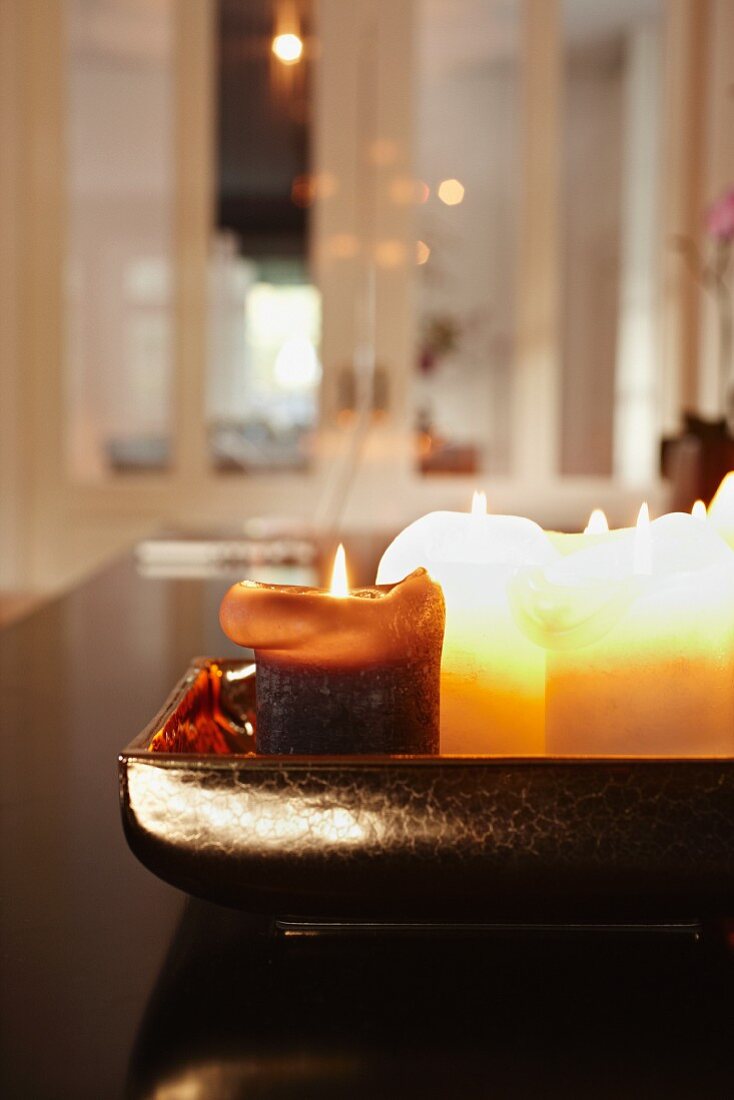 Lit candles in ceramic dish; interior in blurred background