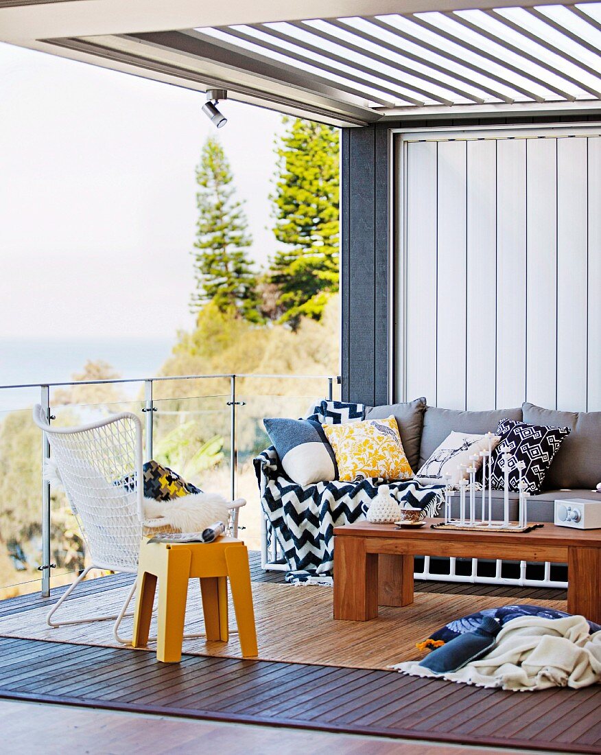 Indoor-Sitzgruppe auf moderner, pergolaüberdachter Terrasse mit Meerblick