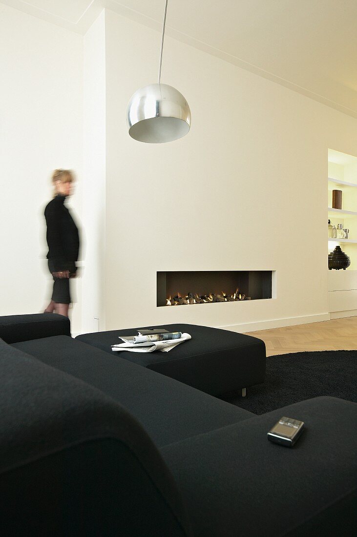 Weisses Wohnzimmer mit schwarzer Sofagarnitur und Einbaukamin