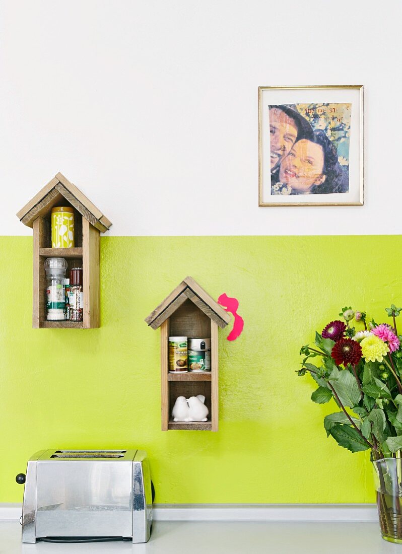 Bird-box-shaped spice racks on green-painted kitchen wall