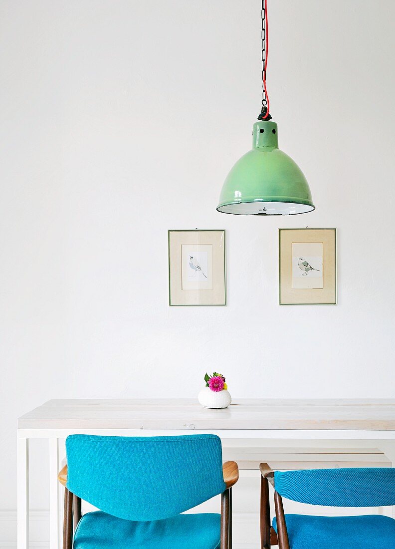 Selbstgebauter Esstisch und Stühle mit blauer Polsterung, darüber Vintage Hängelampe und Bilderrahmen mit Postkarten an der Wand