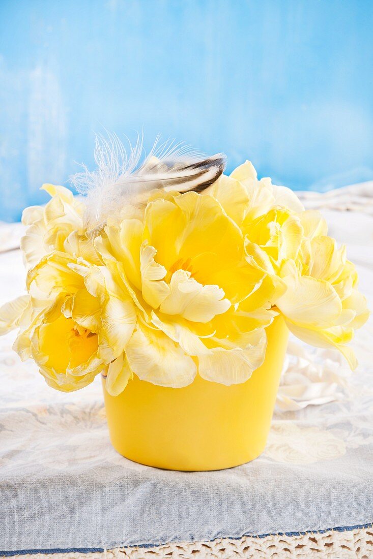 Yellow tulips and feathers in flower pot