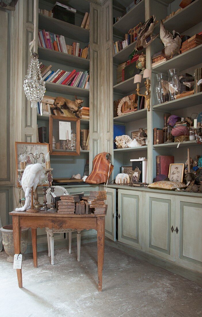 A built-in cupboard filled with antique living accessories for sale in an old French country house