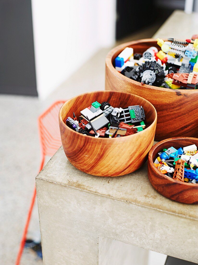 Lego pieces in wooden bowls on corner of concrete kitchen counter