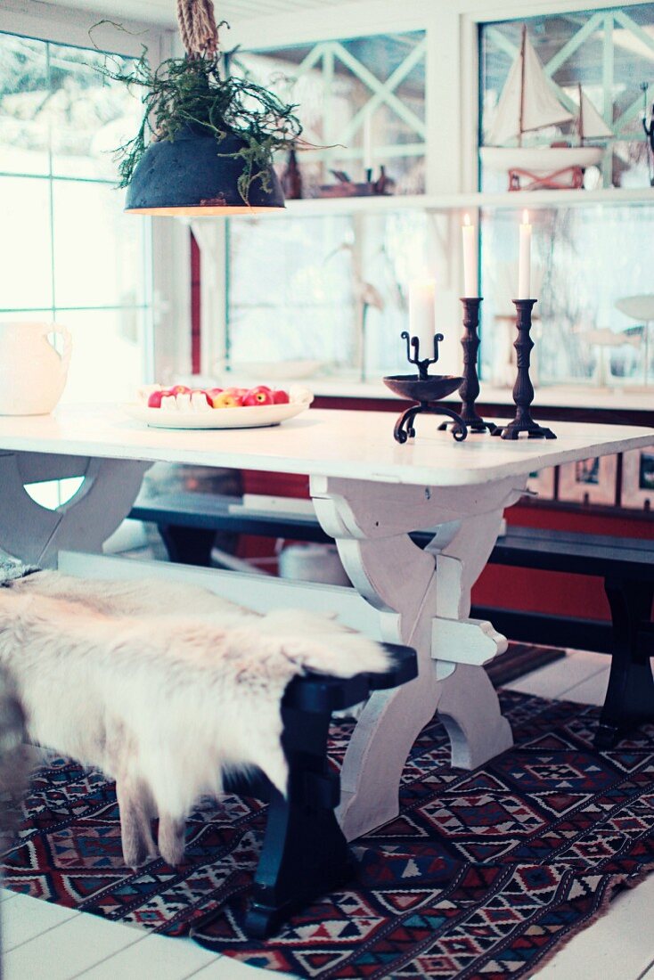 Dining area in Scandinavian country-house atmosphere with rustic dining table and fur on bench